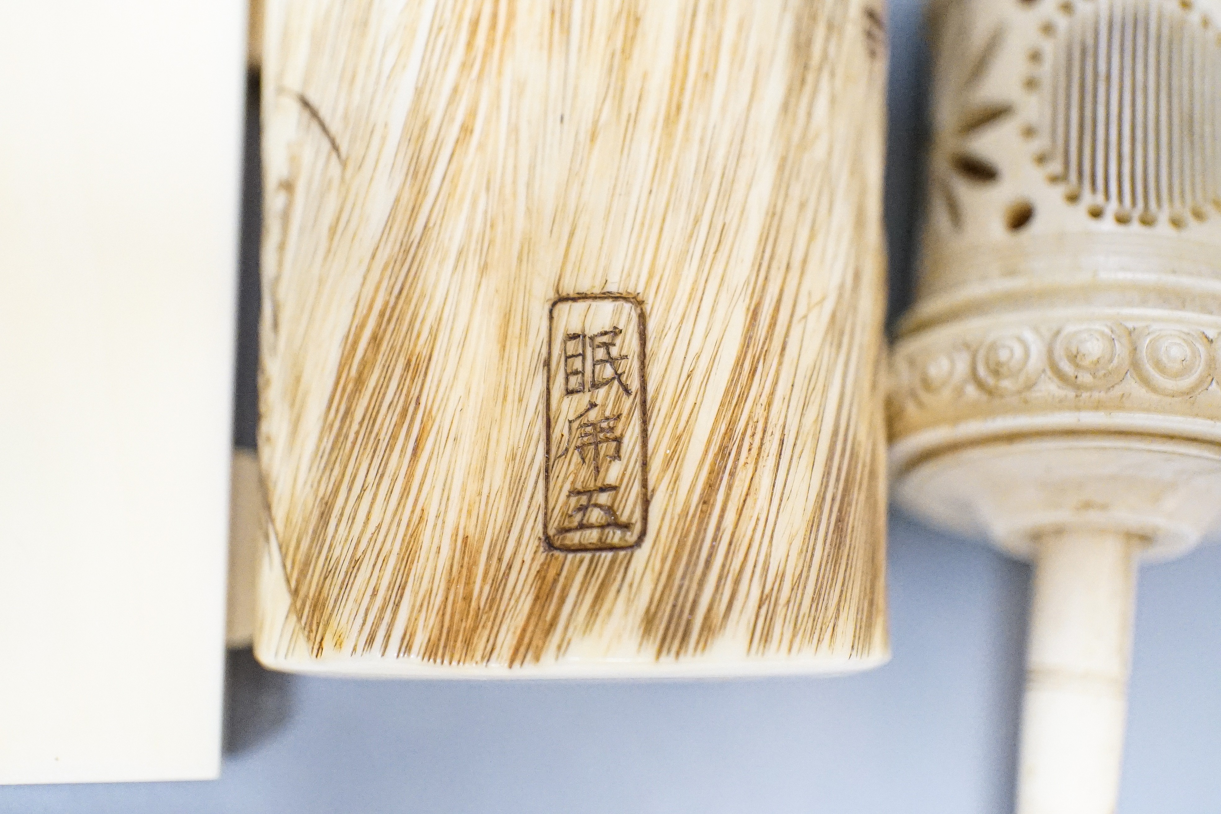 Three Japanese Ivory figures of men, a similar bezique marker, a Japanese staghorn single section inro with ivory manju, a Chinese ivory carving and a bone needlework container